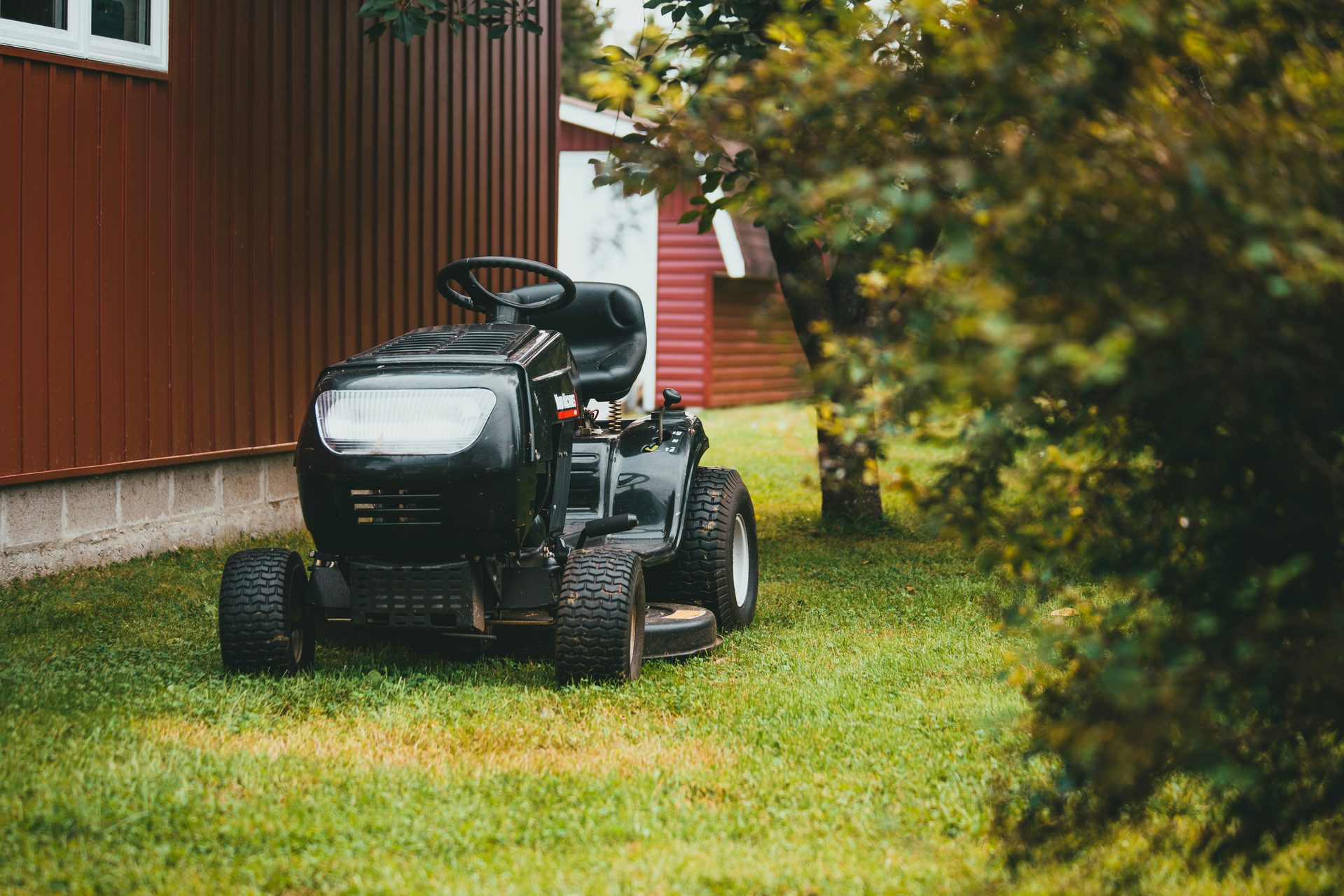 Ride-on mower on a neat lawn beside a timber shed